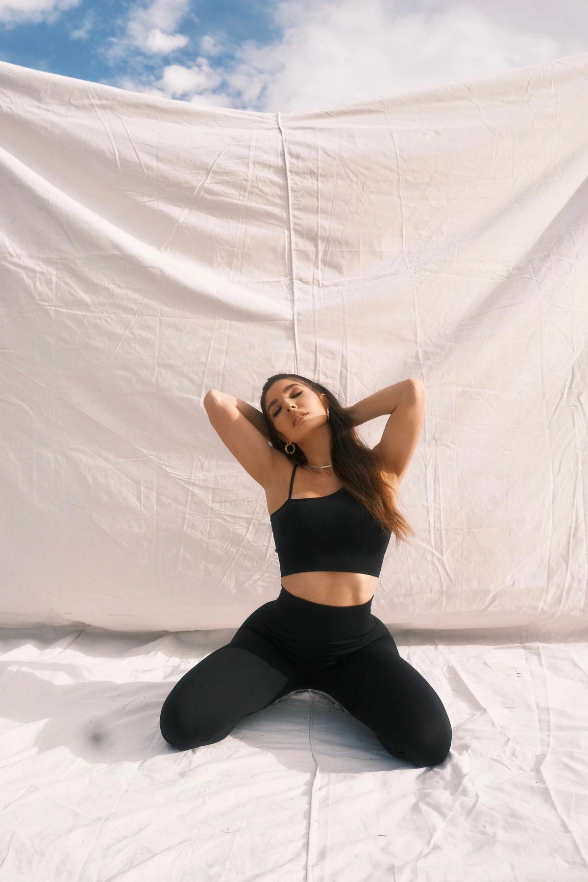 Black activewear campaign against an ivory fabric backdrop.